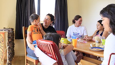 Whānau sitting around the kitchen table talking.